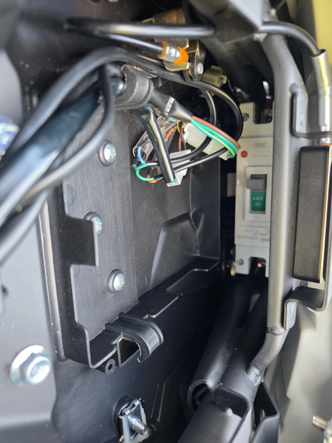 Main circuit breaker beneath the pillion seat, photographed from behind the motorcycle.